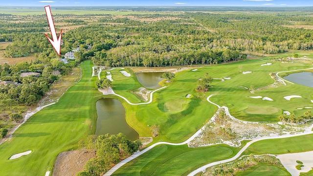 birds eye view of property featuring view of golf course, a water view, and a wooded view