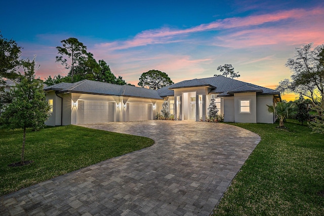 prairie-style home featuring a garage, a front yard, decorative driveway, and stucco siding