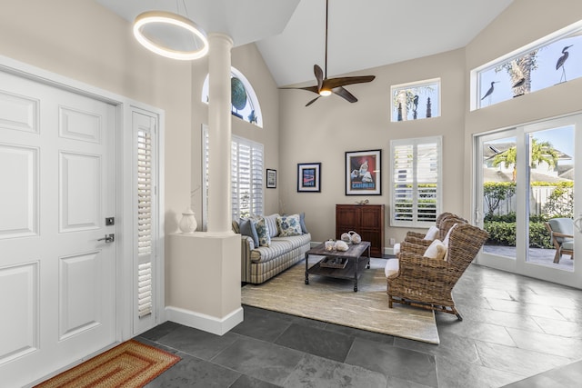 entryway featuring baseboards, plenty of natural light, high vaulted ceiling, and ornate columns