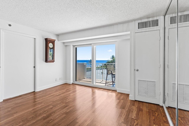 interior space featuring access to exterior, wood finished floors, visible vents, and a textured ceiling