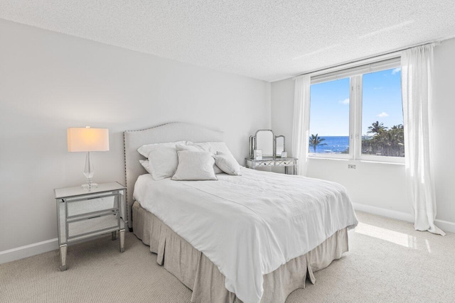 bedroom with light colored carpet, baseboards, and a textured ceiling