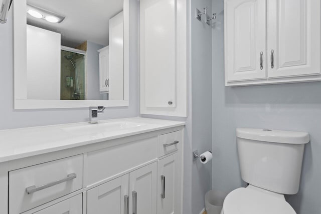 full bath featuring toilet, a stall shower, and vanity