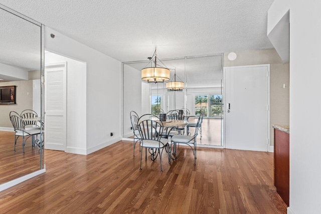 dining area with baseboards, a textured ceiling, an inviting chandelier, and wood finished floors