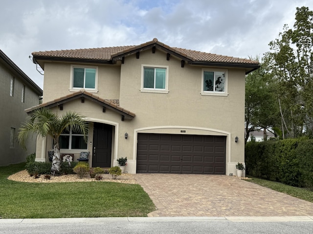 mediterranean / spanish house featuring decorative driveway, stucco siding, an attached garage, a tiled roof, and a front lawn