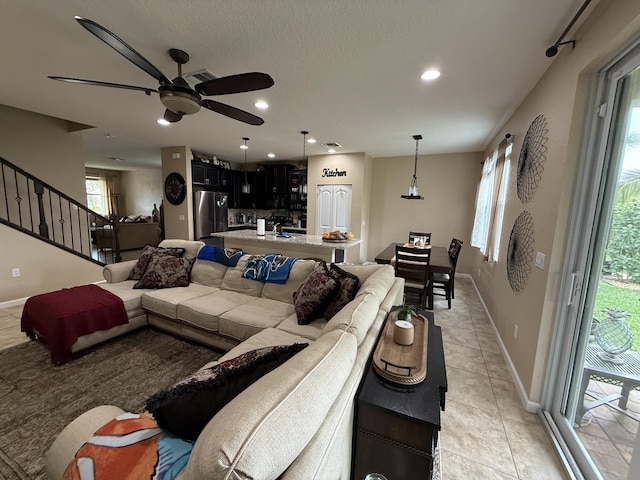 living room with light tile patterned floors, a textured ceiling, recessed lighting, baseboards, and stairway