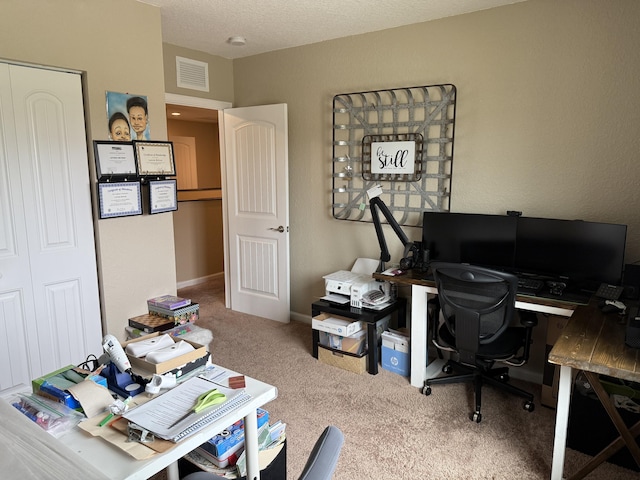 office area with a textured ceiling, carpet, visible vents, and baseboards