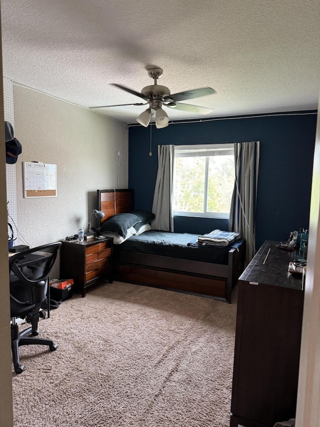 carpeted bedroom featuring a ceiling fan, a textured wall, and a textured ceiling