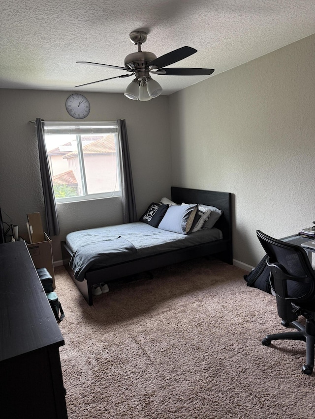 carpeted bedroom featuring baseboards, a ceiling fan, a textured ceiling, and a textured wall