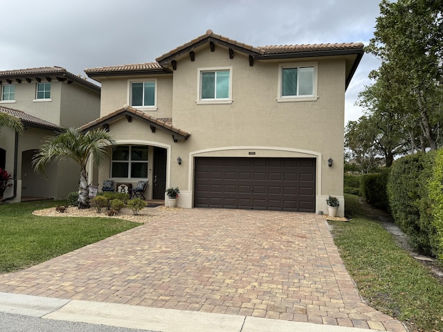 mediterranean / spanish-style home with decorative driveway, a tiled roof, an attached garage, and stucco siding