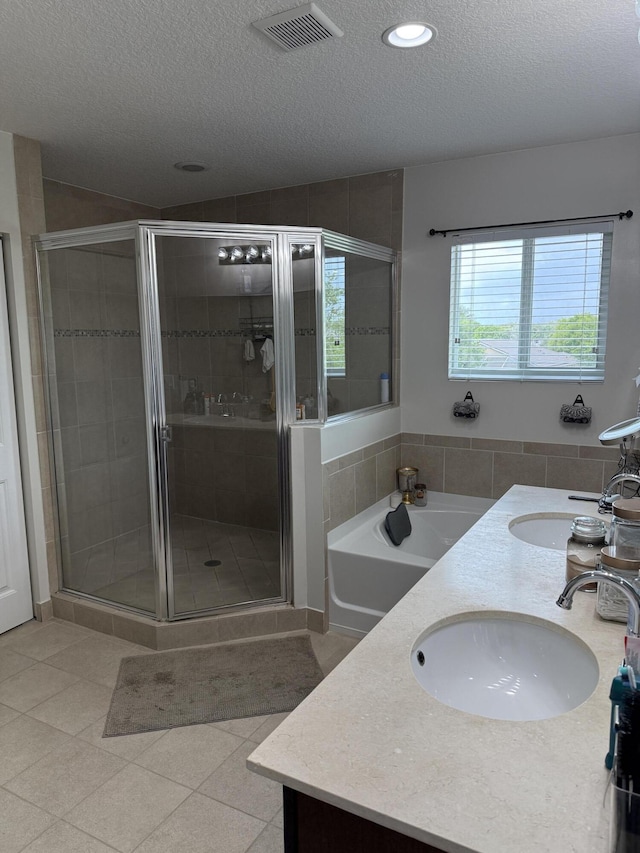 bathroom with a textured ceiling, a sink, visible vents, and a shower stall