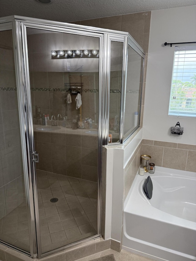 full bath with a stall shower, a textured ceiling, and a bath