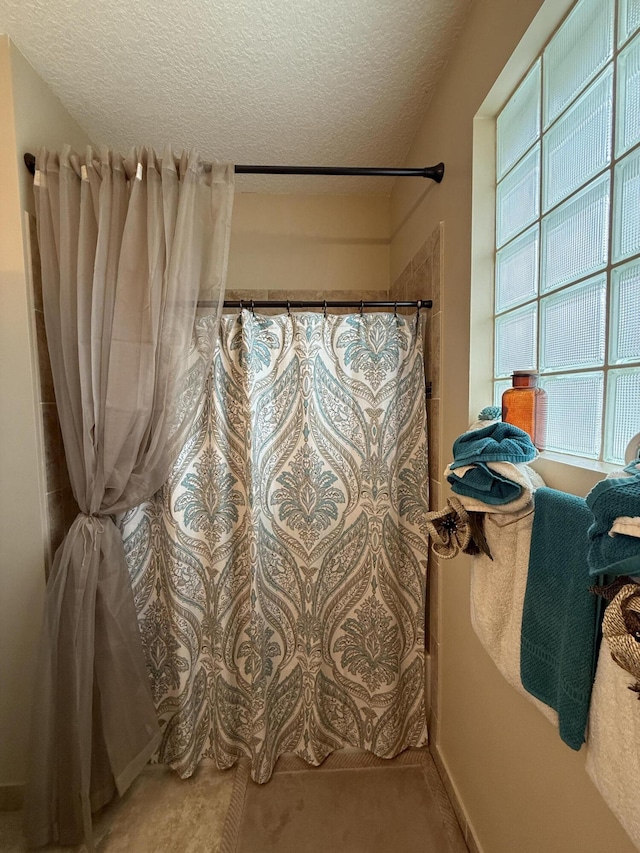 bathroom with a textured ceiling and a shower with shower curtain