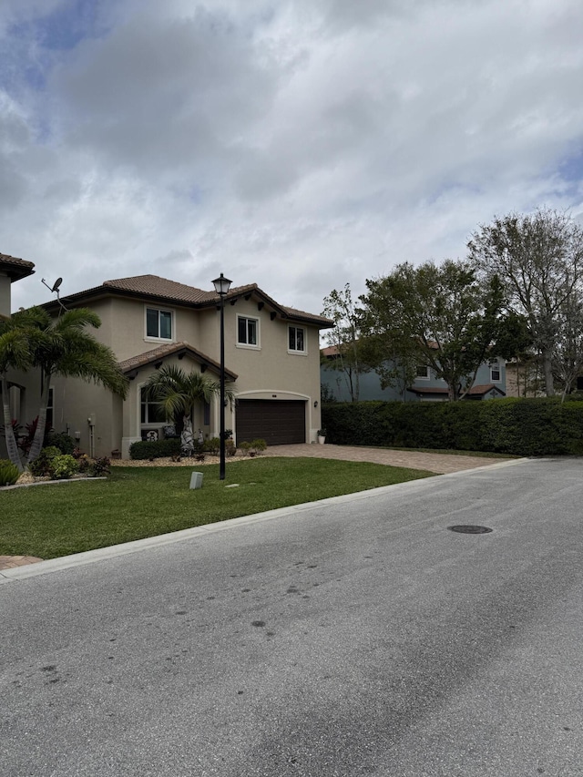 view of front of property featuring a front yard, an attached garage, and stucco siding