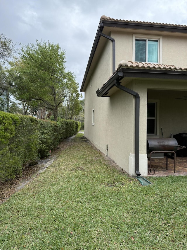 view of side of home with a lawn and stucco siding