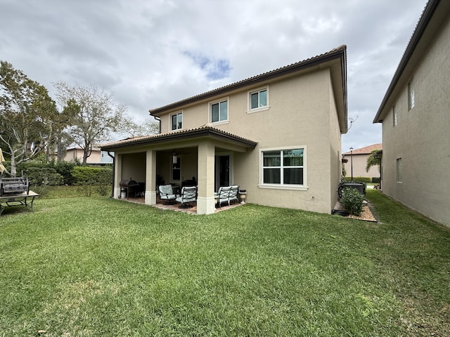 back of house with a patio area, a lawn, and stucco siding