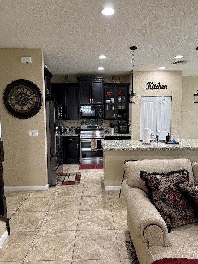 kitchen with pendant lighting, light tile patterned floors, glass insert cabinets, dark cabinets, and black appliances