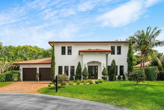 mediterranean / spanish-style home featuring decorative driveway, a garage, stucco siding, and a tiled roof