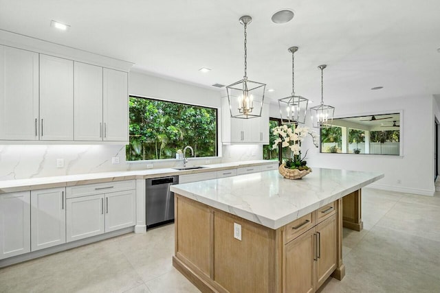 kitchen featuring a sink, a kitchen island, stainless steel dishwasher, and white cabinetry