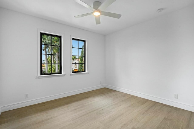 spare room featuring baseboards, ceiling fan, and light wood finished floors