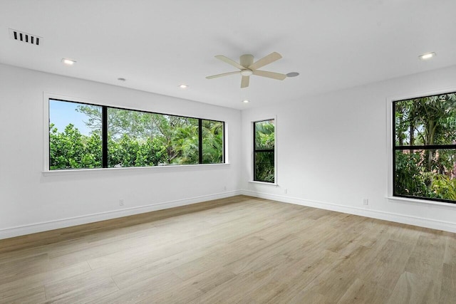 unfurnished room with a wealth of natural light, visible vents, baseboards, and light wood-style flooring