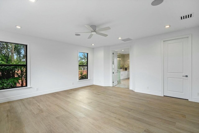 empty room with visible vents, light wood-type flooring, and baseboards