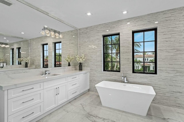 full bathroom with visible vents, marble finish floor, a freestanding bath, and vanity