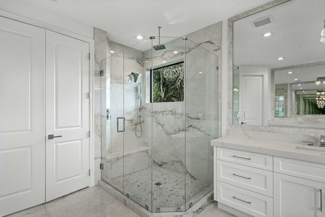 bathroom with a marble finish shower, visible vents, and vanity