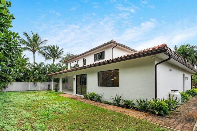 back of property featuring fence, a tile roof, stucco siding, a lawn, and a patio