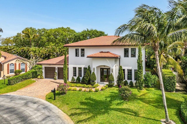 mediterranean / spanish-style house featuring stucco siding, a front yard, decorative driveway, and a garage