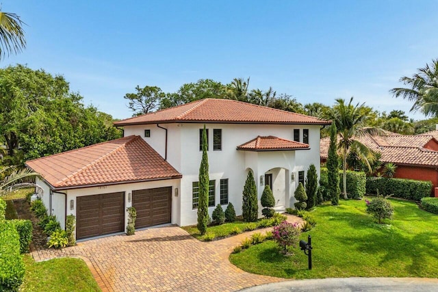 mediterranean / spanish house with stucco siding, a tile roof, decorative driveway, an attached garage, and a front yard