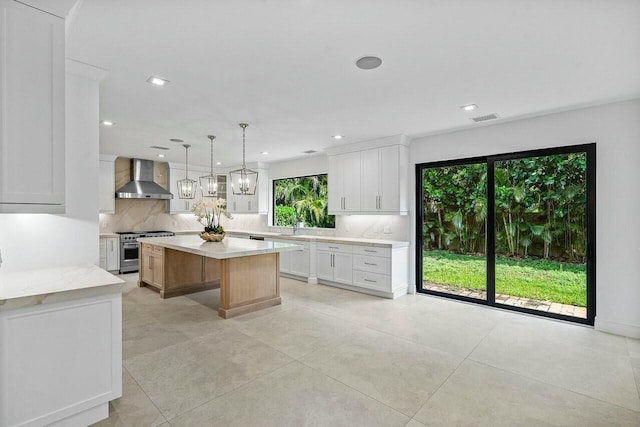 kitchen with visible vents, a center island, decorative backsplash, stainless steel stove, and wall chimney exhaust hood