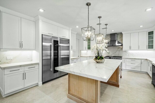 kitchen with wall chimney range hood, a center island, white cabinets, and high end refrigerator