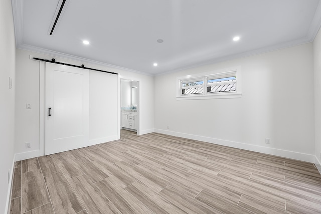 unfurnished bedroom featuring light wood finished floors, a barn door, baseboards, and crown molding