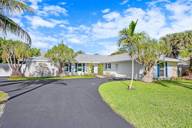 ranch-style house with an attached garage, driveway, a front lawn, and stucco siding