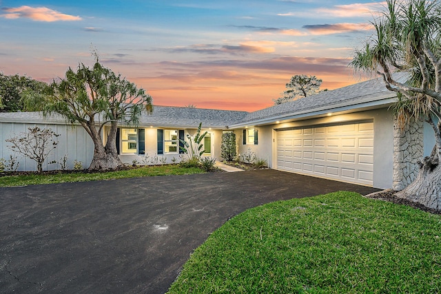 ranch-style house with a garage, a front yard, driveway, and stucco siding