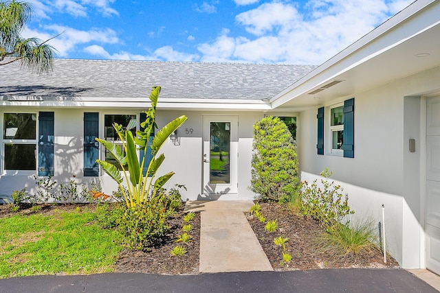 property entrance with roof with shingles and stucco siding