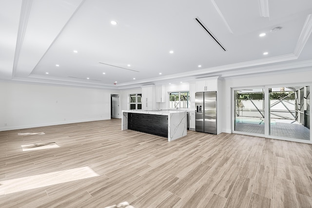 unfurnished living room with ornamental molding, baseboards, a healthy amount of sunlight, and light wood finished floors