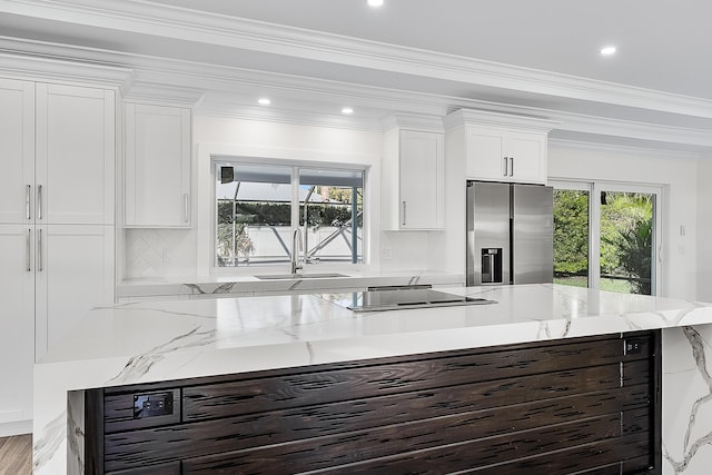 kitchen featuring tasteful backsplash, ornamental molding, white cabinets, a sink, and stainless steel fridge