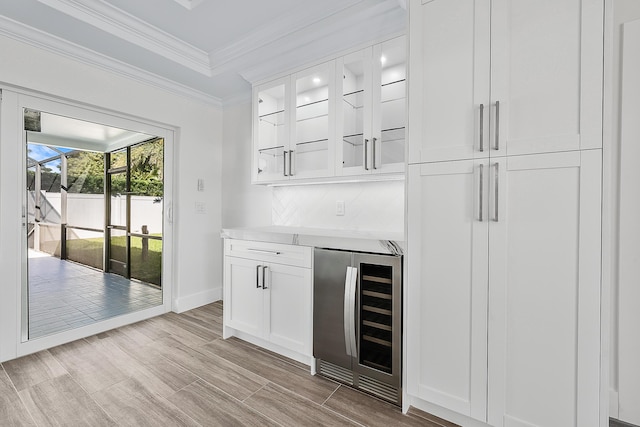 bar featuring crown molding, a dry bar, decorative backsplash, wood tiled floor, and beverage cooler