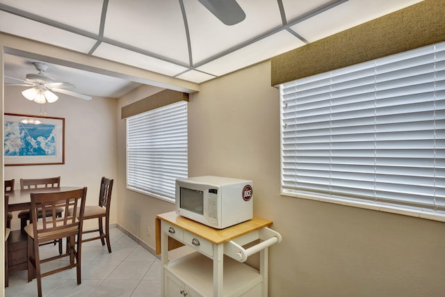 dining space with ceiling fan, baseboards, and light tile patterned floors