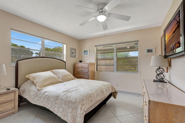 bedroom with ceiling fan, a textured ceiling, baseboards, and light tile patterned floors