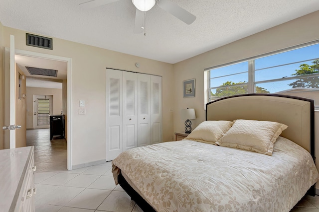 bedroom with a textured ceiling, visible vents, a closet, and light tile patterned flooring