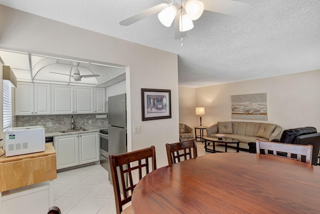 dining room with light tile patterned floors, a textured ceiling, and a ceiling fan