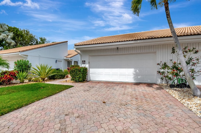 view of front of house with a garage, a tiled roof, and decorative driveway