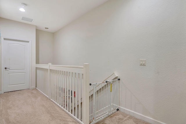 hallway with carpet, visible vents, and baseboards