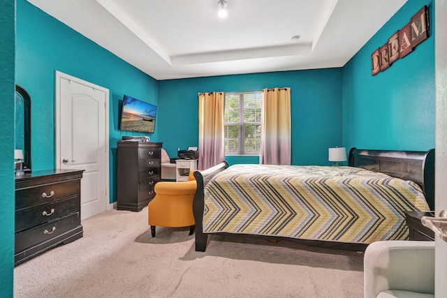 bedroom with carpet floors and a raised ceiling