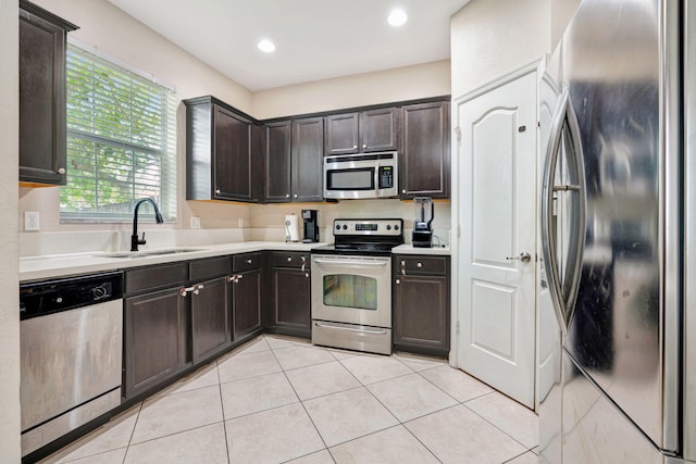 kitchen featuring light tile patterned floors, light countertops, appliances with stainless steel finishes, a sink, and dark brown cabinetry