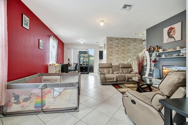 living area featuring a textured wall, visible vents, and light tile patterned flooring