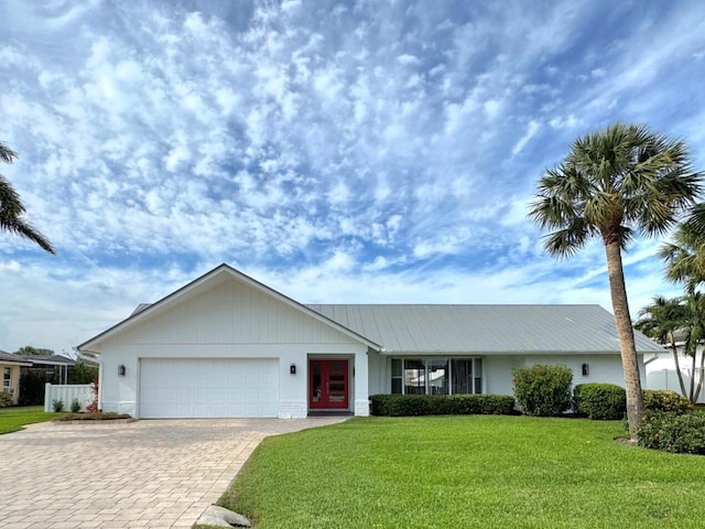 single story home featuring a garage, decorative driveway, metal roof, and a front lawn