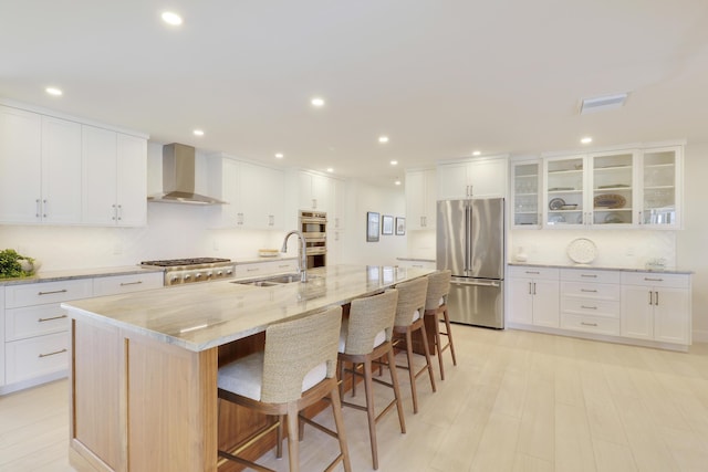 8579 SE Sabal St, Hobe Sound, FL 33455 - kitchen featuring appliances with stainless steel finishes, a sink, wall chimney range hood, a breakfast bar, and light stone counters